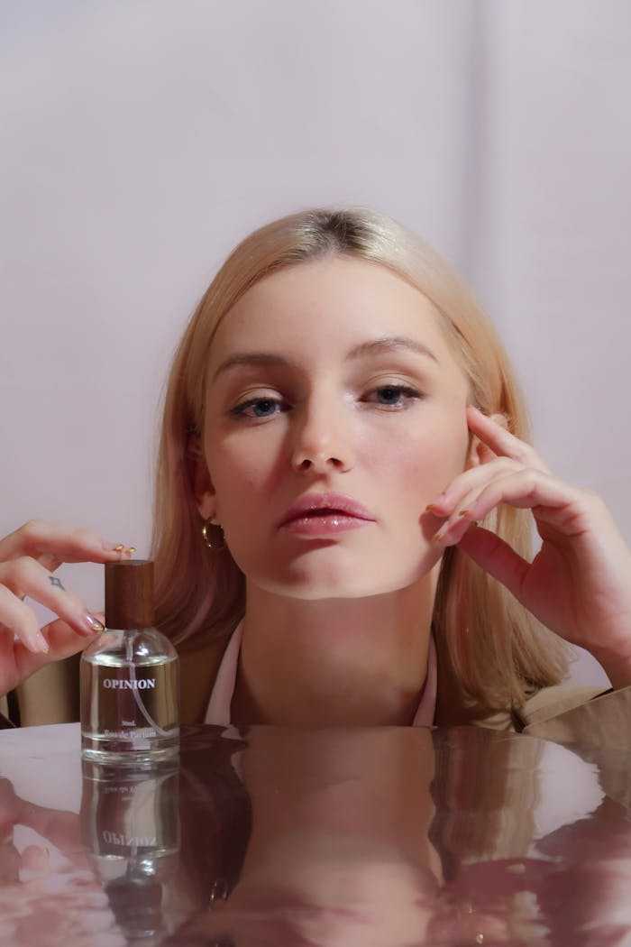 Stylish headshot of a blonde woman posing with a perfume bottle, perfect for beauty and lifestyle themes.